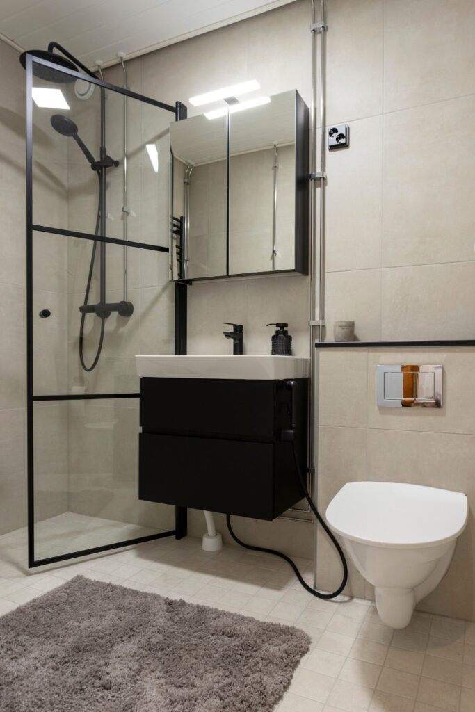 Kuvassa remontoitu kylpyhuone tyylikkäillä mustilla ja vaaleilla materiaaaleilla.